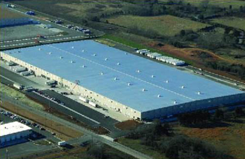 Blue-roof logistics facility beside access road