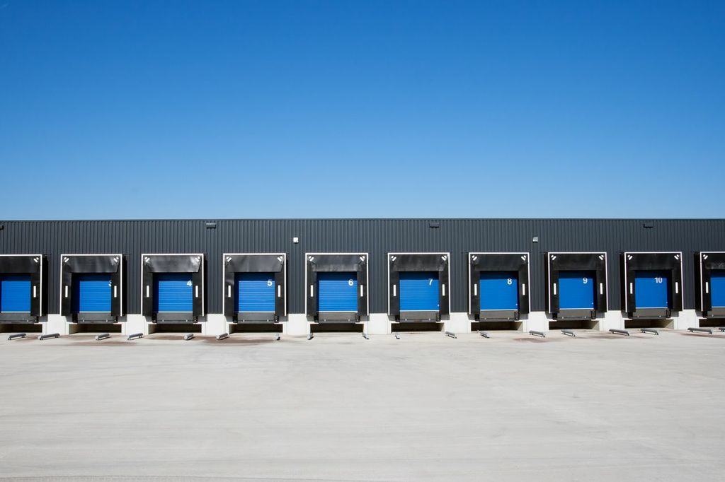 A row of blue doors in front of a warehouse.