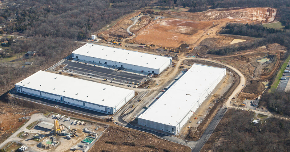 An aerial view of a large warehouse in a wooded area.